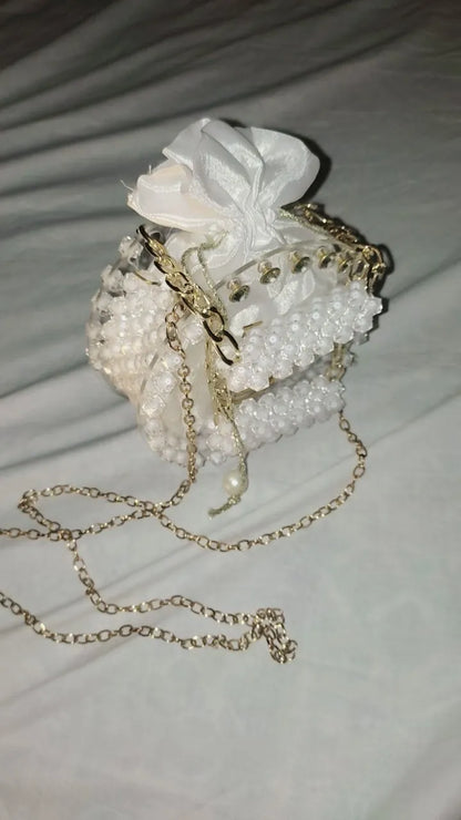 Decorative handbag with pearls and a white flower on a light background