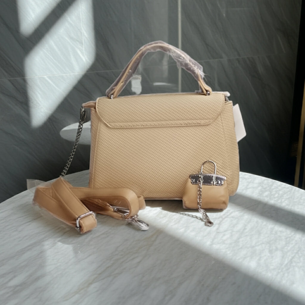Beige handbag with a detachable strap on a textured surface