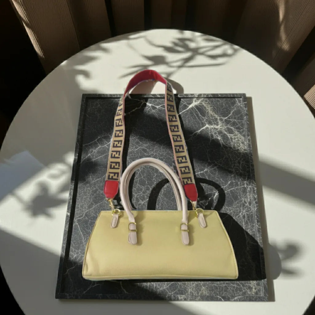 Beige handbag with a red and beige strap on a black marble surface
